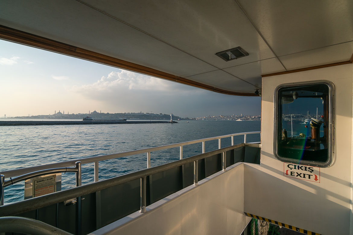 View from a ferry's deck. There is a long pier close to the ferry and Istanbul in the background.