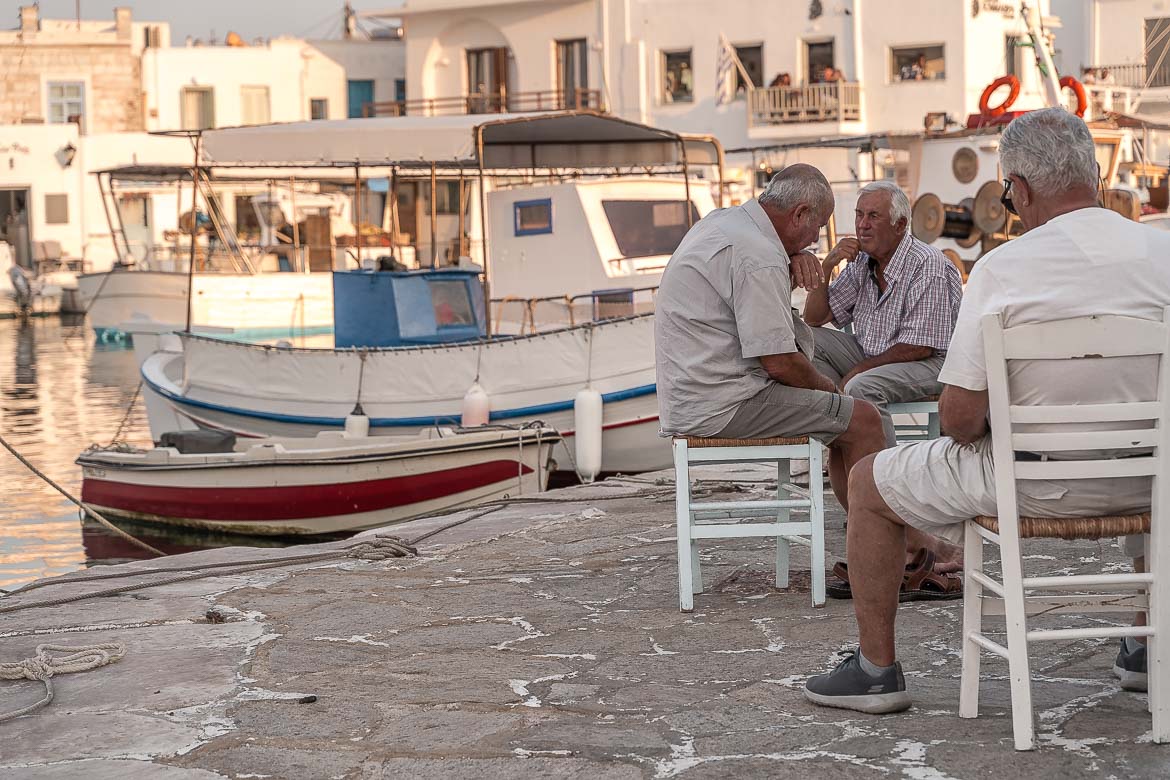 This image shows three locals hanging out at the old port of Naoussa in Paros. Depicting local life is one of the most precious things about travel photography.