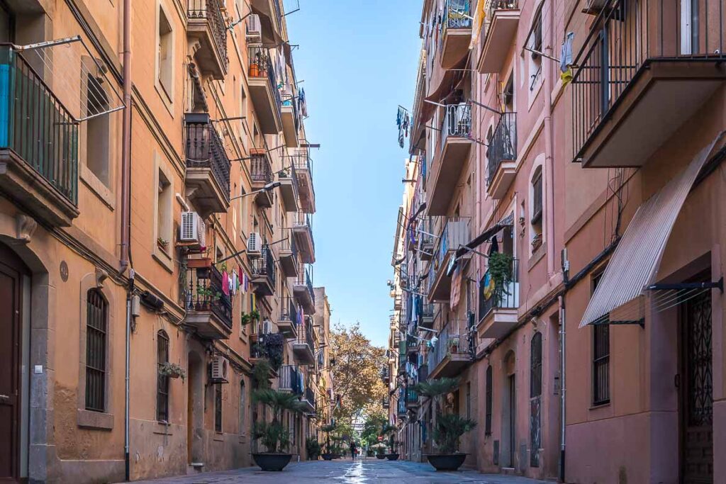 This image shows a quiet street in Barcelona lined by tall buildings on both sides. We chose a photo shot in Barcelona as the featured image for our article about Airbnb ethical issues because Barcelona is one of the cities that has suffered the most due to the Airbnb effect.