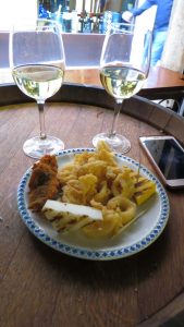 The photo shows a dish of fried seafood and two glasses of white wine in a bacaro in Venice, Italy.