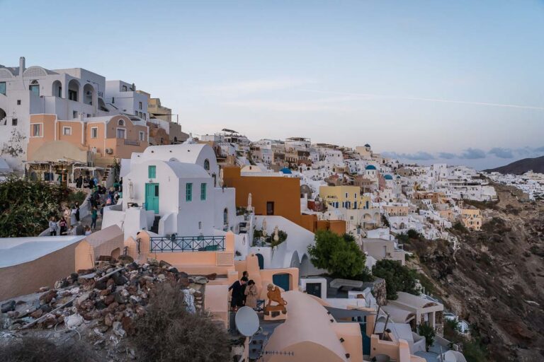 This image shows the village of Oia perched atop the dramatic volcanic rock. In the center of the photo, we can see Sophia Castle View Hotel. Oia is one of the best areas to stay in Santorini, especially for first timers.