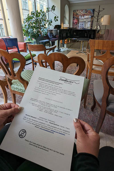 The concert room at Beethoven Hotel. Maria holds the concert program.