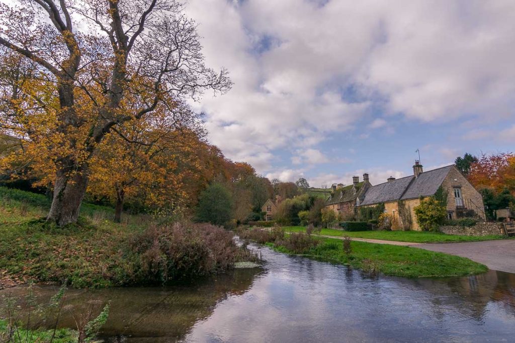 Best villages in the Cotswolds: A complete guide This is Upper Slaughter, one of the prettiest villages in the Cotswolds. It is autumn, the leaves of the trees are brown-orange. There are a couple of honey-coloured cottages to the right. In the middle of the photo, we can see the ford, a narrow stream at one of the village's crossroads. We consider this a very representative image of the Cotswolds. This is why we chose it as the featured image for our article Best villages in the Cotswolds: A complete guide.