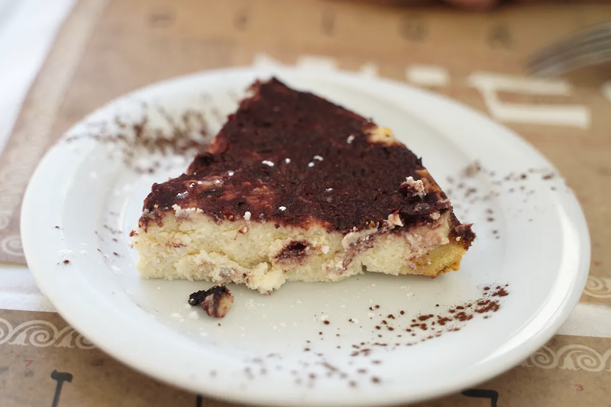 A close-up of a piece of Crostata di Ricotta e Visciole on a white plate.