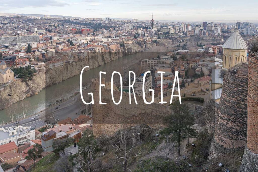 Panoramic view of Tbilisi and the river from Narikala Fortress. There's overlay text that reads Georgia.
