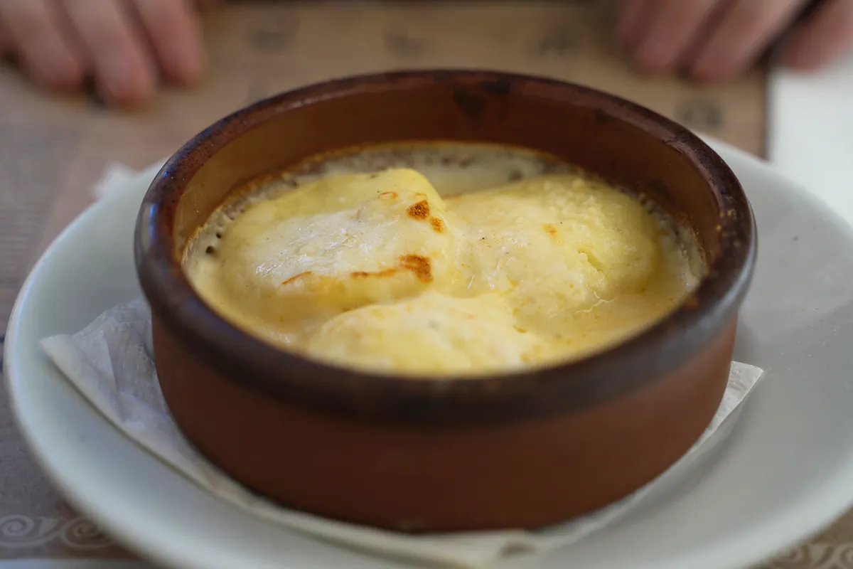 A close-up of a clay bowl with Gnocchi alla Romana.