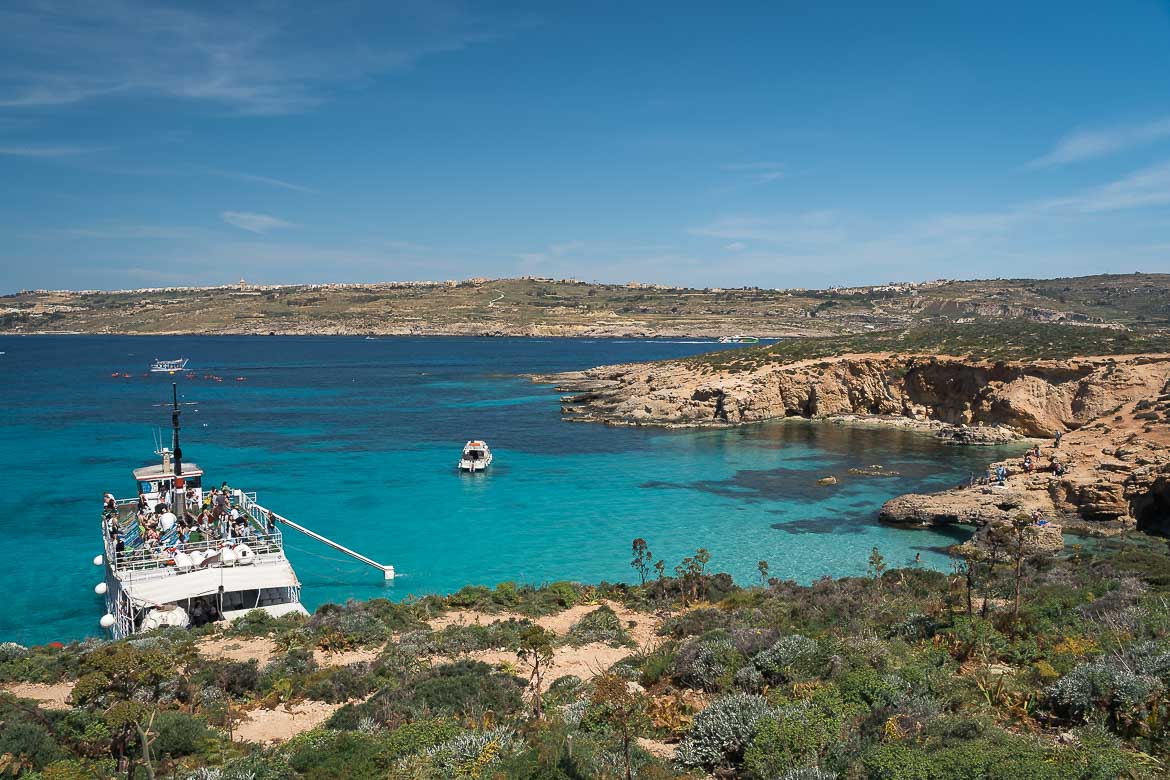 This image shows a tourist boat mooring at the turquoise waters of Comino.