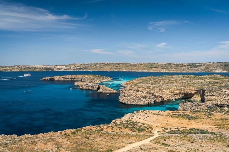 This image shows a panoramic view of the Blue Lagoon with the Gozo Channel in the background.