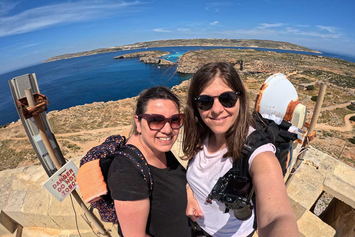 This image shows a selfie photo of Maria and Katerina taken at Saint Mary's tower terrace. A panoramic view of the Blue Lagoon is in the background.
