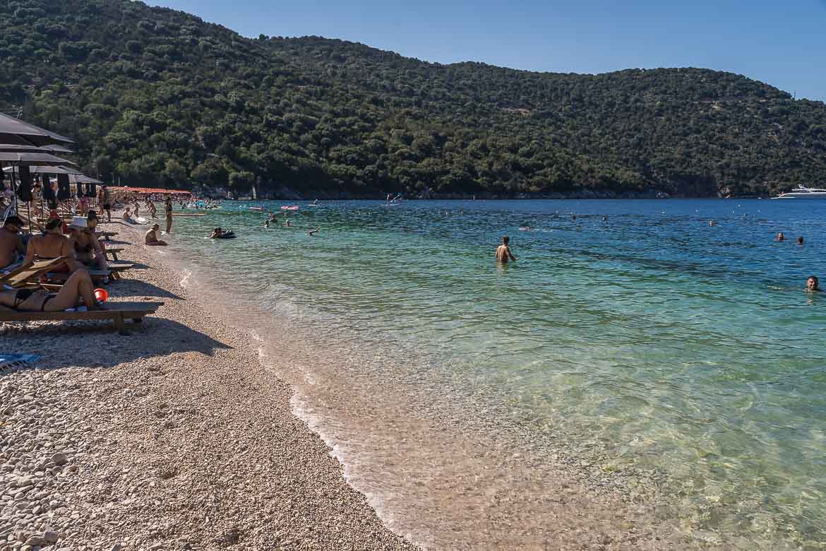 View of Antisamos Beach from eye level. The beach has white pebbles and deep green waters.