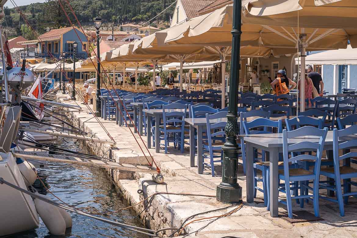 A restaurant with blue tables and chairs at Fiskardo's harbour.