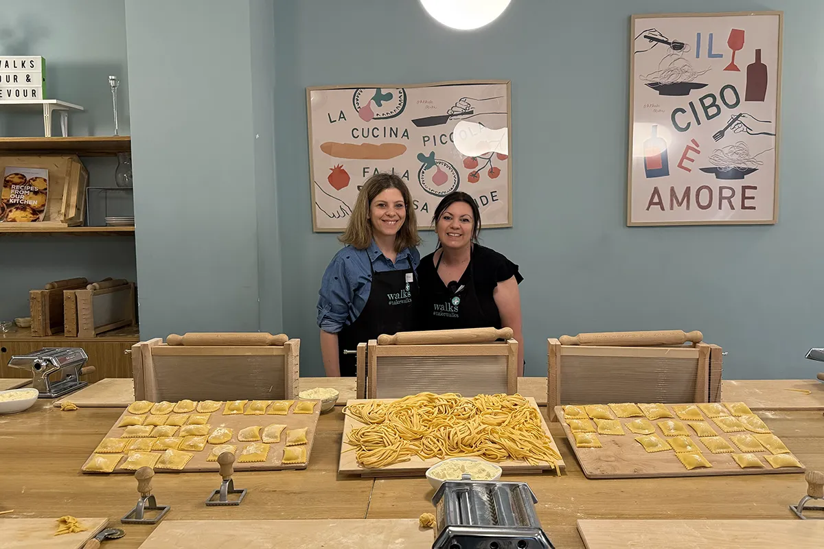 Katerina and Maria smiling to the camera and posing with freshly made pasta at the pasta-making class.