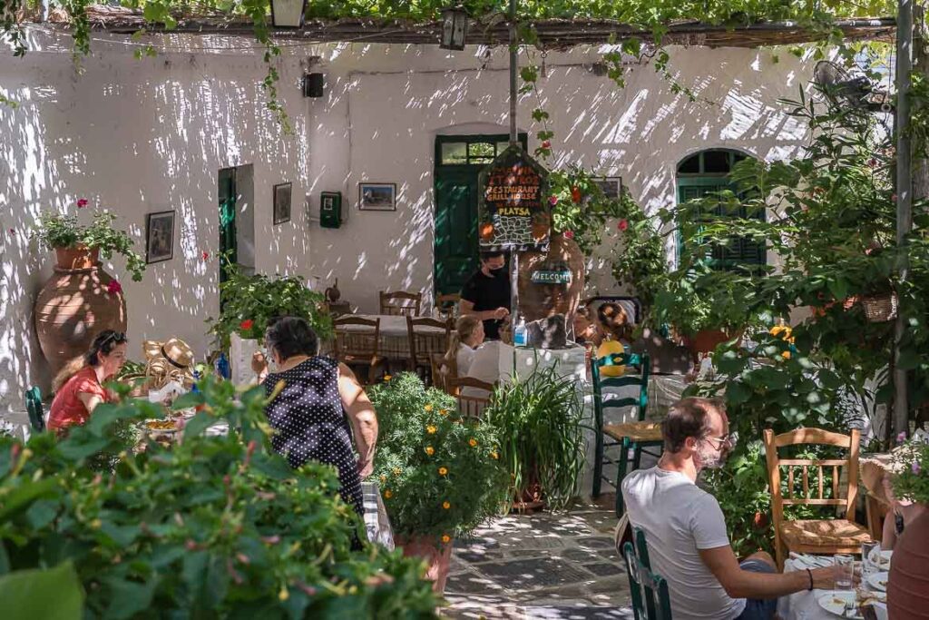 View of the quaint courtyard with plants and climbing vine in a restaurant in Koronos.