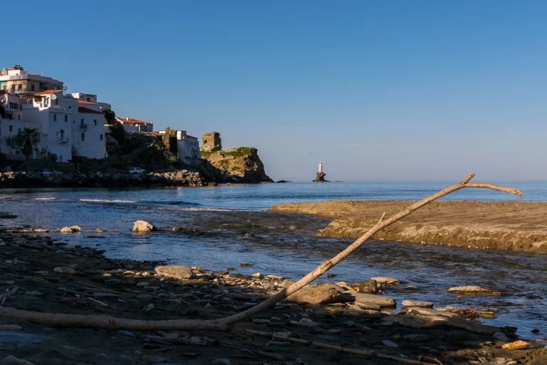 View to Chora and Tourlitis Lighthouse from Paraporti Beach. We've chosen this to be the featured image of our article 15 unique things to do in Andros Greece and full Andros Guide.