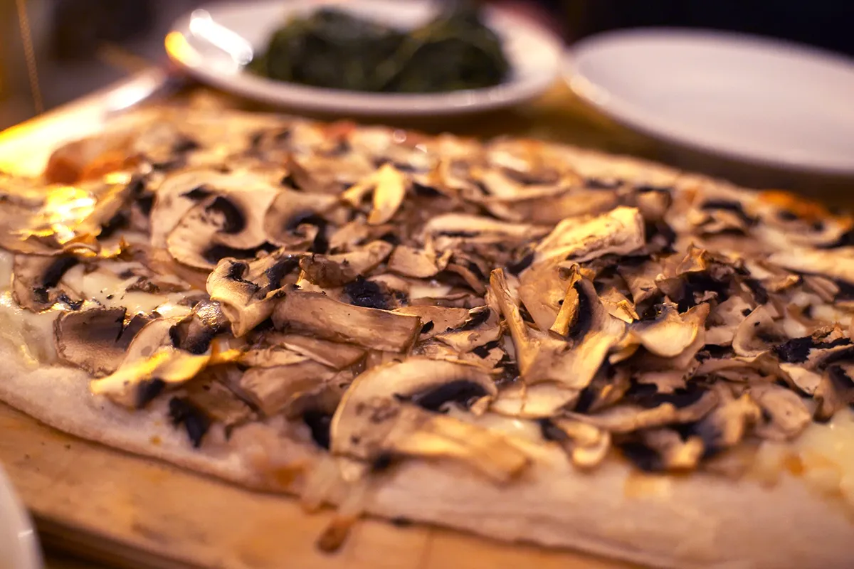 A close-up of a Pinsa Romana topped with mushrooms.