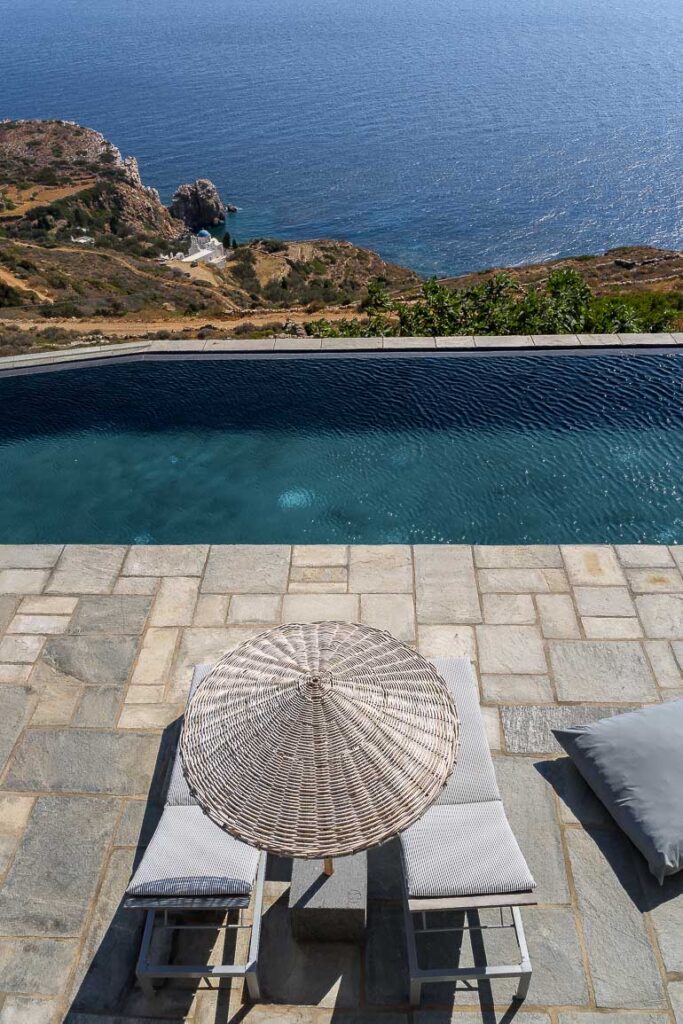 This image shows the swimming pool area of Verina Hotel in Sifnos with view to Poulati church.