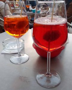 This photo shows a table in a bar in Venice with two Spritz cocktails on it.
