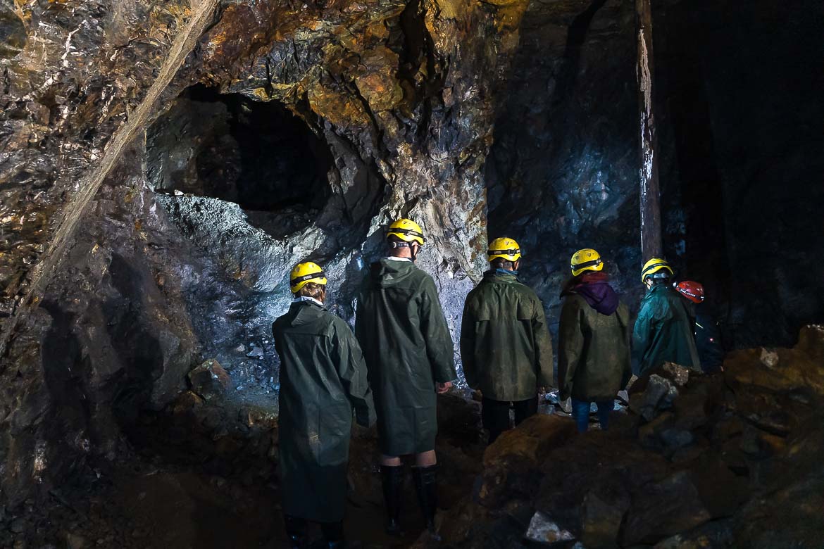 A group of six people wearing yellow helmets and green anoraks in the Johannes mine.