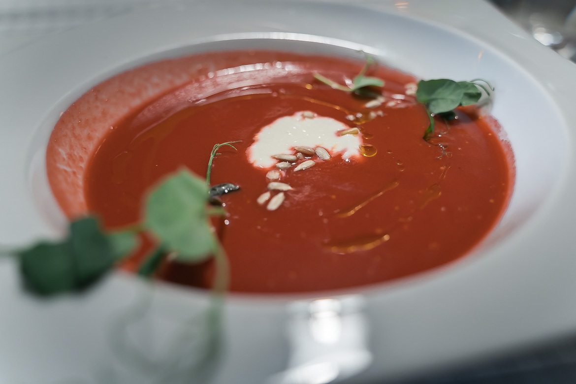 A beetroot soup with sour cream and decorative leaves.