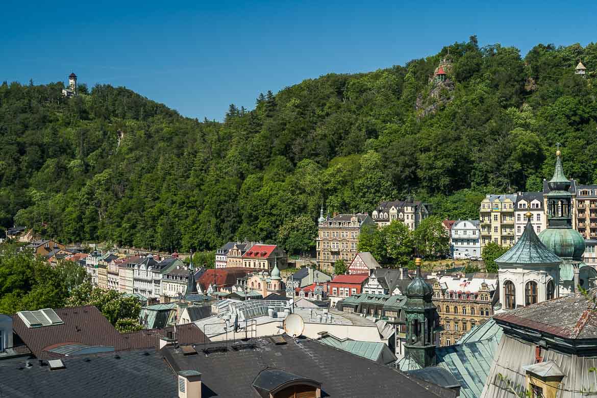 A panoramic view of Karlovy Vary. A green mountain embraces the beautiful buildings. 