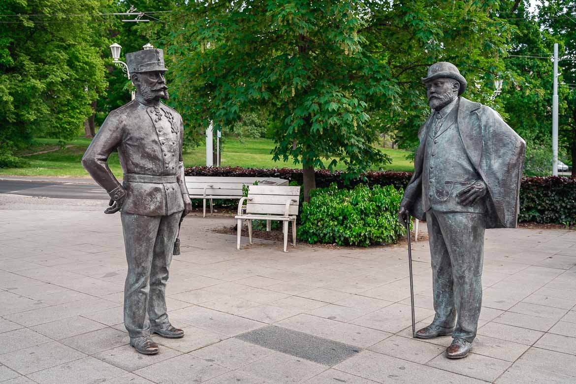 The human-sized royal statues of the British King Edward VII and the Emperor Franz Joseph I in the park in Marianske Lazne. The Austrian Emperor stands on the left wearing his military uniform and King Edward on the right wearing a costume, a coat, a hat and holding a cane.