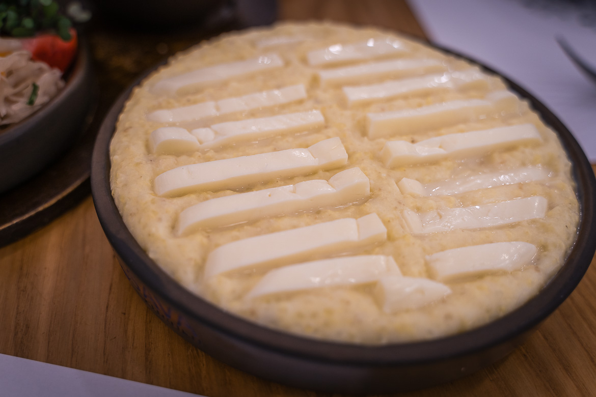 A close up of a porridge with thick slices of cheese on top. 