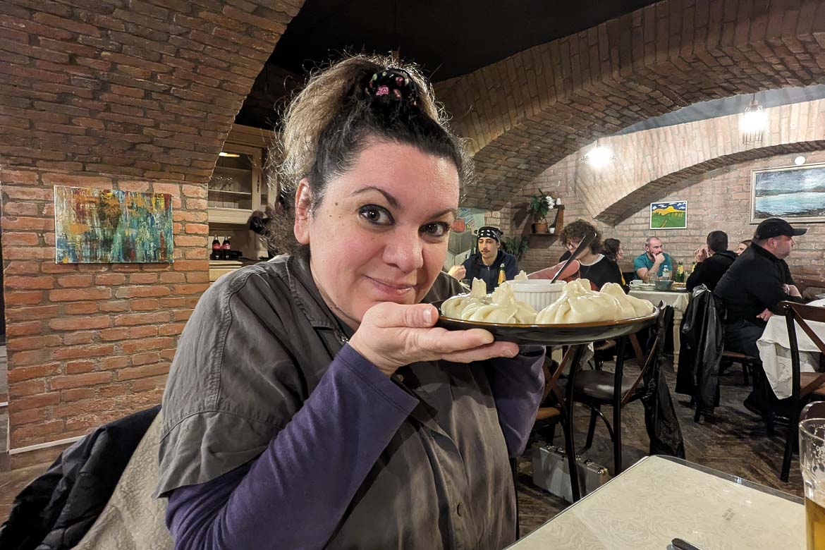 Maria holding a plate of Khinkali, smiling to the camera. 