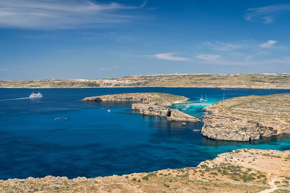 Panoramic view of the Blue Lagoon with Gozo in the background. The Gozo-Malta ferry is crossing the channel.