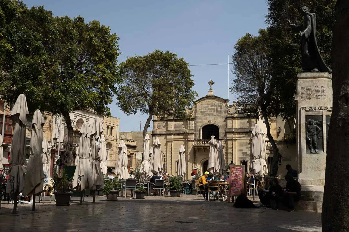 The Independence Square in Gozo with many café tables and umbrellas.