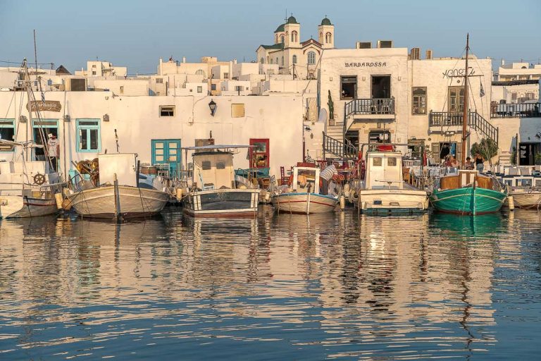 This is a panoramic shot of the Old Port in Naoussa at sunset. There are many traditional boats which reflect on the calm sea water. In the background, the whitewashed buildings of Naoussa. We believe that this photo is very characteristic of Paros and this is why we chose it as the featured image for our article on what to do in Paros Greece.